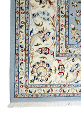 Detalle de guarda y flecos de alfombra persa celeste y beige con motivos florales