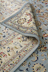 Detalle de textura y pliegue de alfombra persa celeste con guarda beige y diseño floral