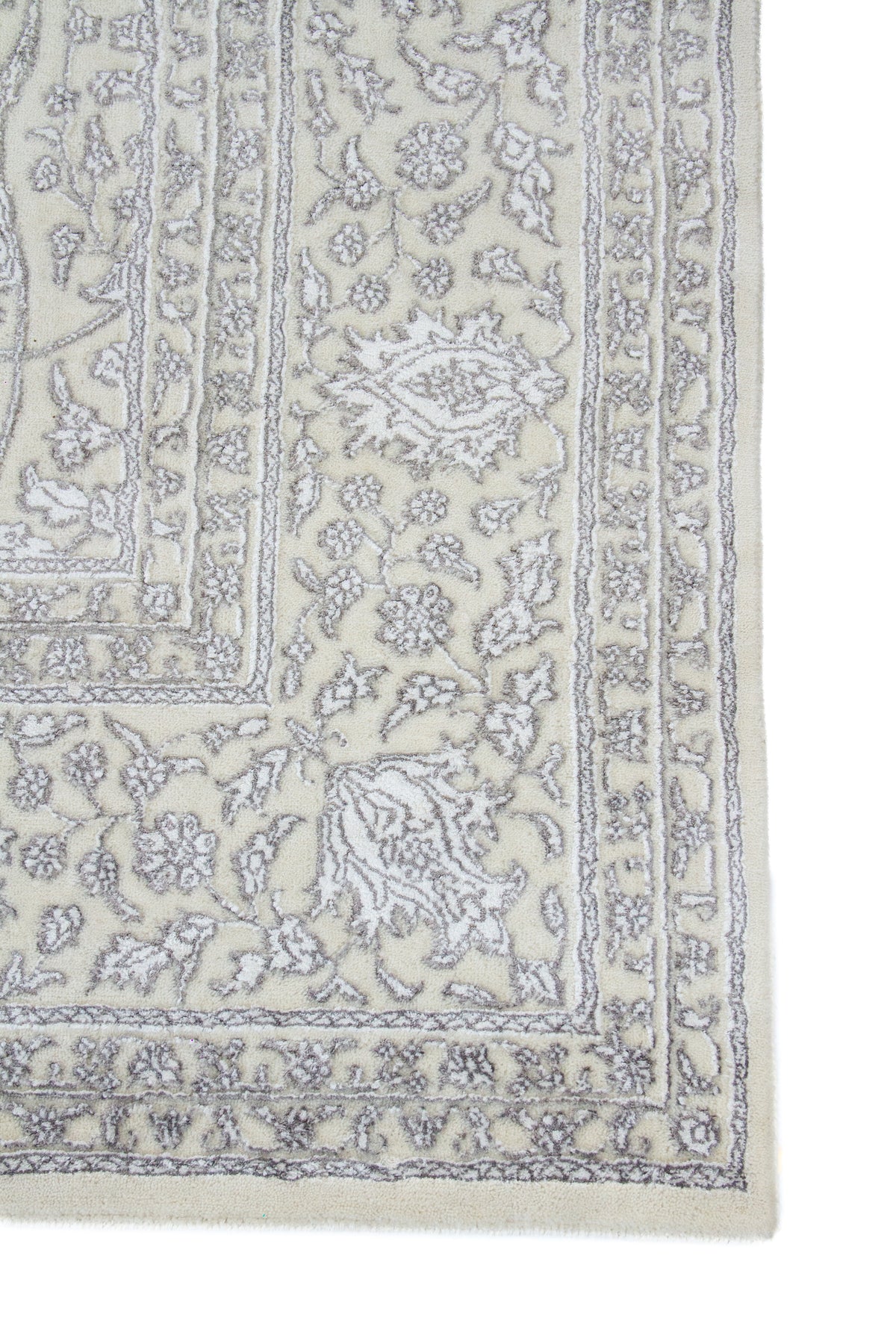 Detalle de guarda de alfombra persa beige con motivos florales en gris claro