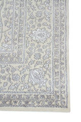 Detalle de guarda de alfombra persa beige con motivos florales en gris claro