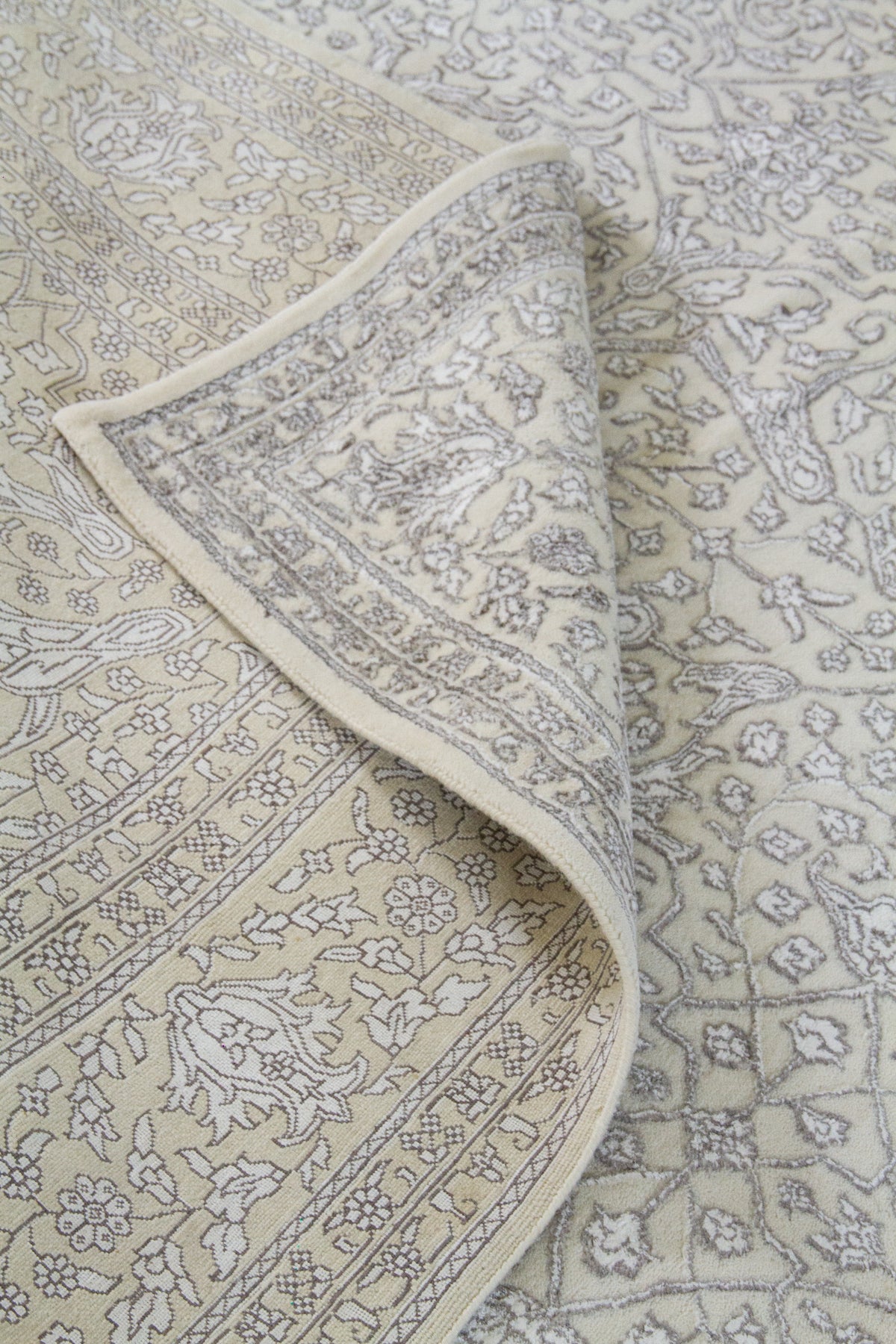 Detalle de textura y pliegue de alfombra persa beige con guarda ornamental