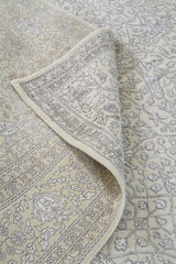 Detalle de textura y pliegue de alfombra persa beige con guarda ornamental