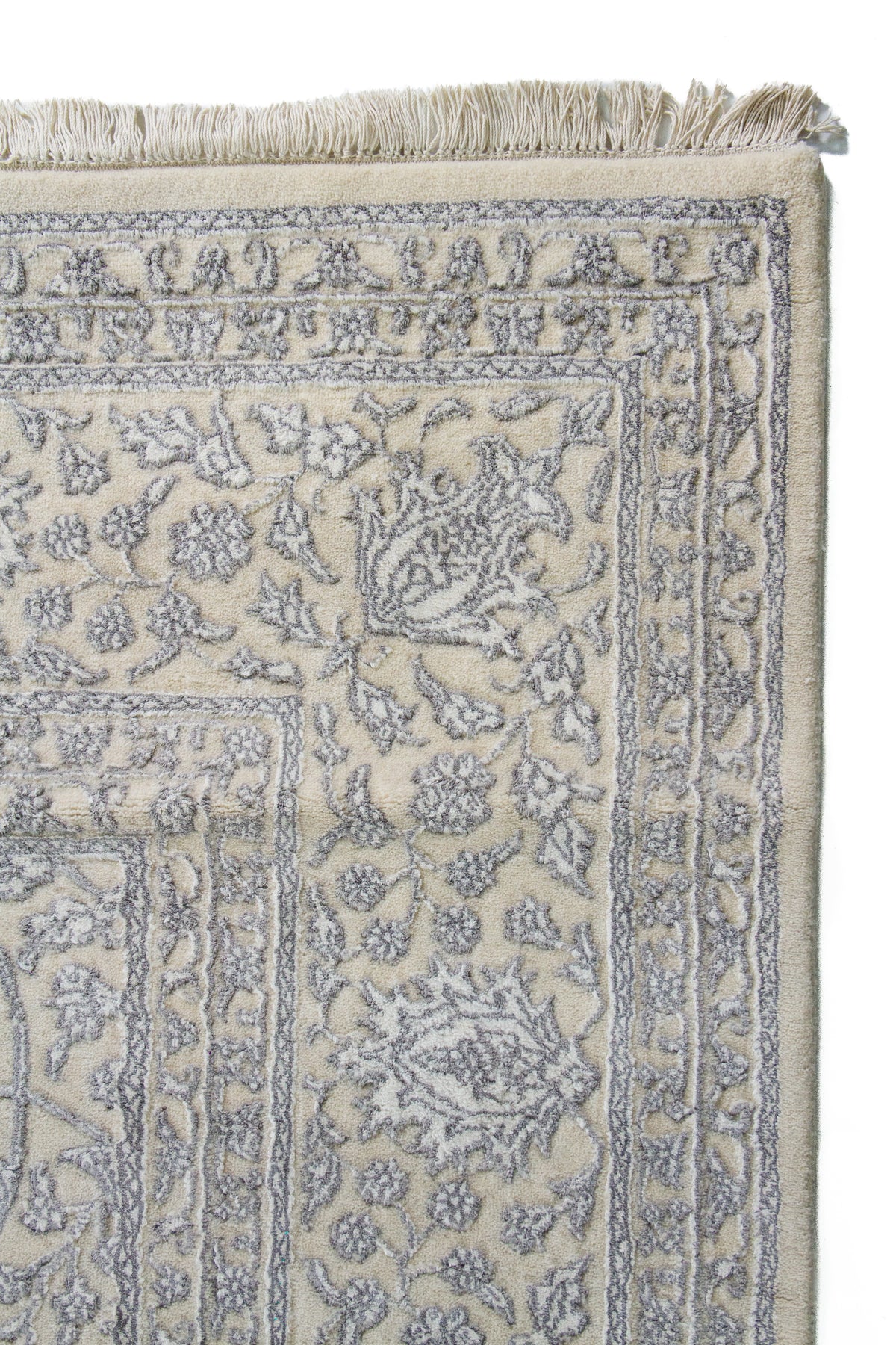 Detalle de guarda y flecos de alfombra Persa Nain beige con motivos florales