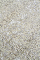 Detalle de textura y diseño floral de alfombra Persa Nain en beige y blanco