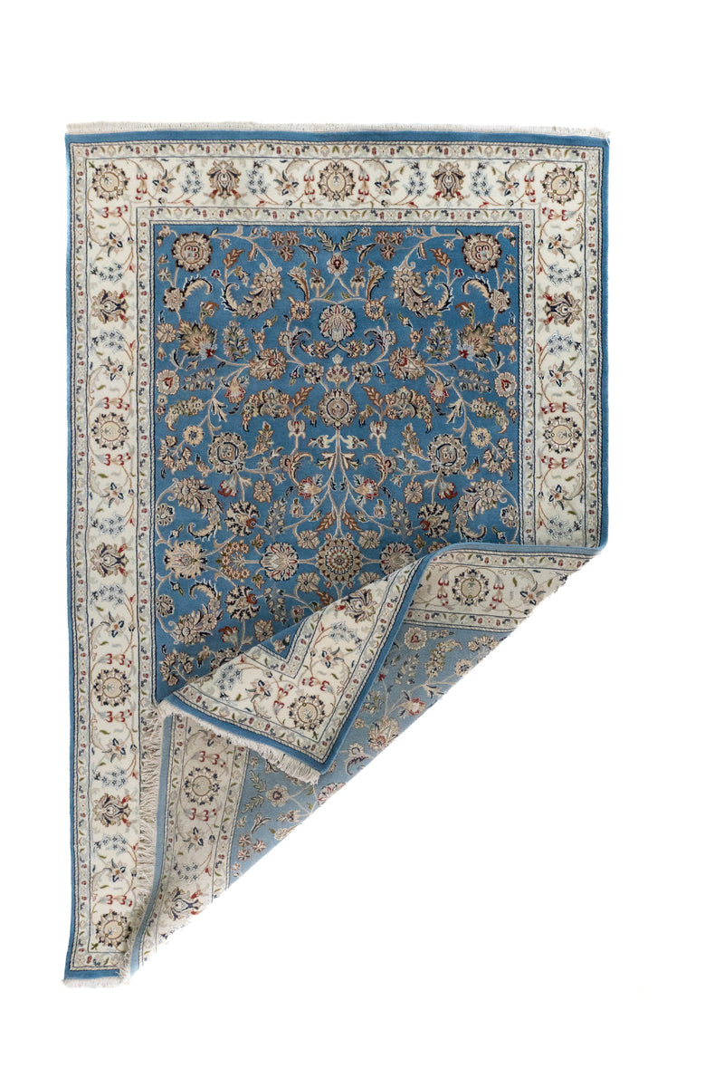 Alfombra Persa Nain con esquina doblada, guarda blanca y diseño floral en tonos celeste