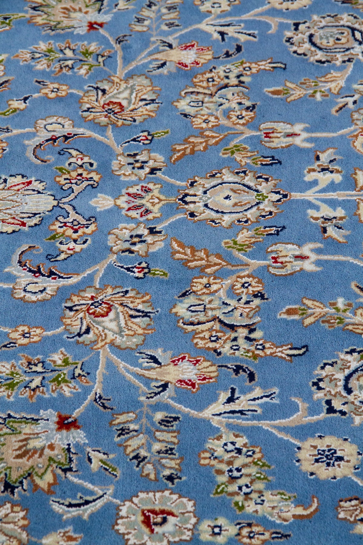 Detalle de textura de alfombra persa celeste con motivos florales y arabescos decorativos
