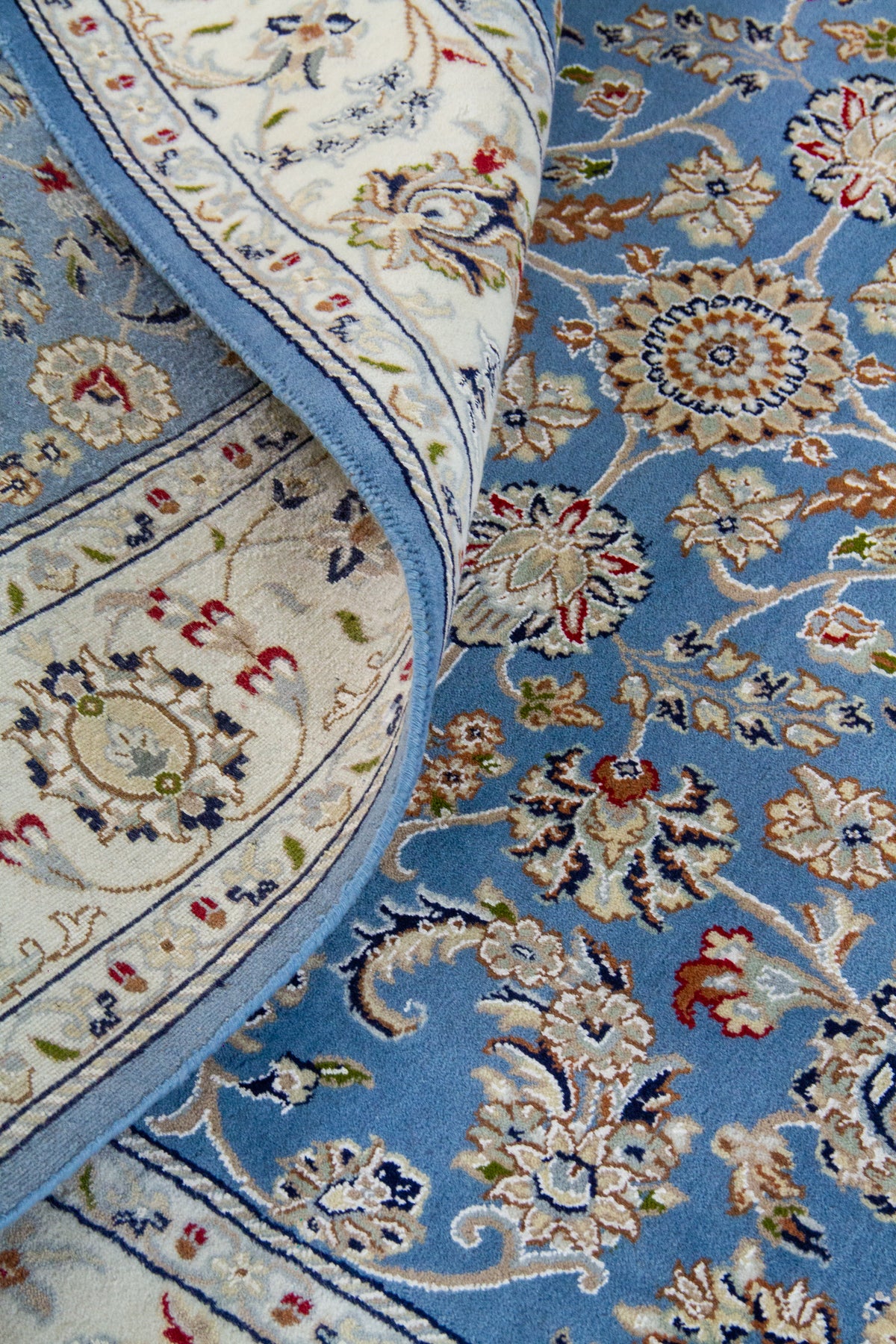 Detalle del diseño floral de alfombra persa azul con guarda blanca y borde decorativo