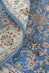 Detalle del diseño floral de alfombra persa azul con guarda blanca y borde decorativo