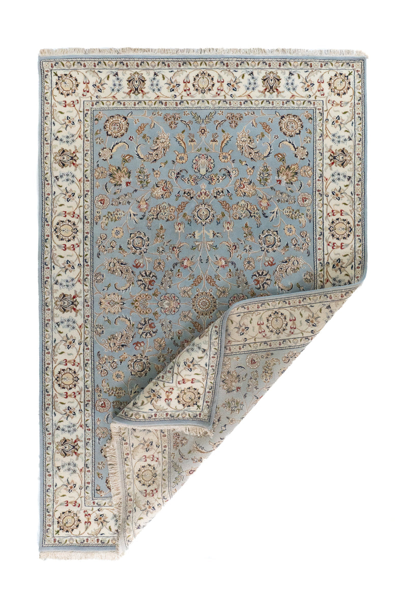 Alfombra Persa Nain con esquina doblada, guarda beige y motivos florales en tonos celestes
