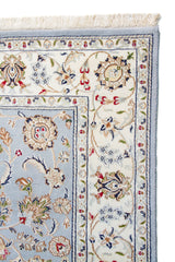 Detalle de guarda y flecos de alfombra persa celeste con diseño floral clásico