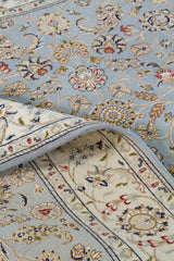 Detalle del diseño floral y reverso de de Alfombra Persa Nain con hojas y arabescos sobre fondo celeste