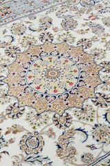 Detalle de textura y medallón central de alfombra persa beige con diseño floral