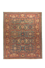 Vista general de una alfombra de inspiración oriental con un campo central en azul, verde y una ancha guarda en tonos rojo. Su composición simétrica combina flores, ramas y ornamentos tradicionales distribuidos con gran equilibrio visual.