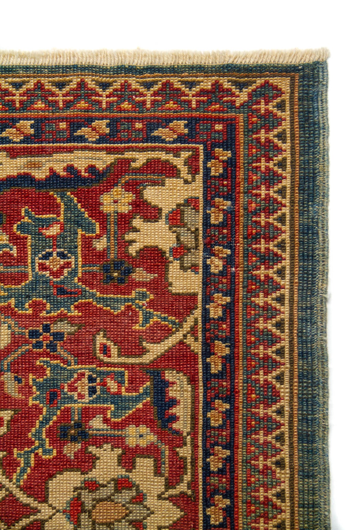 Vista cercana del borde superior donde se distinguen claramente las cenefas, la textura del tejido y la fineza de los motivos decorativos. El contraste entre los tonos cálidos y fríos realza la elegancia de la pieza.