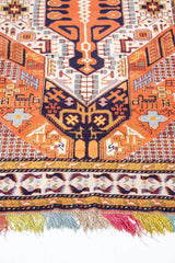 Detalle de flecos multicolor y guarda de alfombra persa geométrica.
