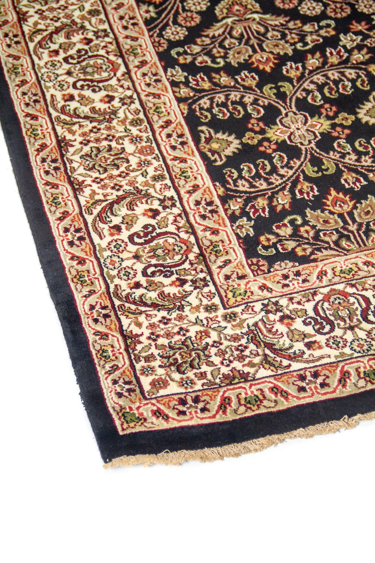 Primer plano de borde de alfombra oriental con guarda blanco suave decorada con arabescos florales sobre fondo negro.