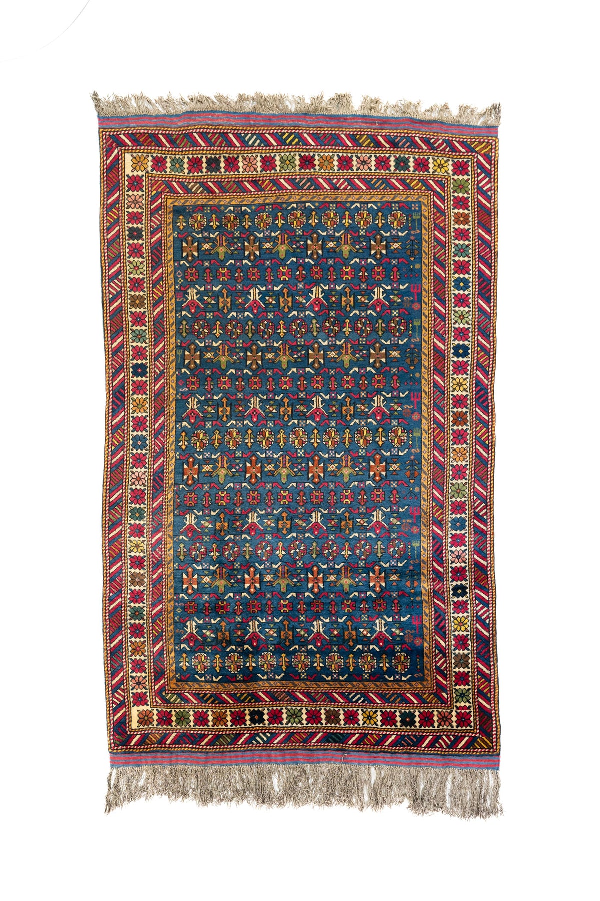 Alfombra oriental rectangular en tono azul intenso con patrones geométricos multicolor y bordes florales decorativos