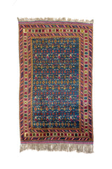 Alfombra oriental rectangular en tono azul intenso con patrones geométricos multicolor y bordes florales decorativos