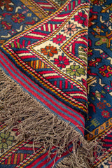 Detalle de flecos y doblez de alfombra mostrando la textura del tejido y el contraste del diseño en tonos vibrantes