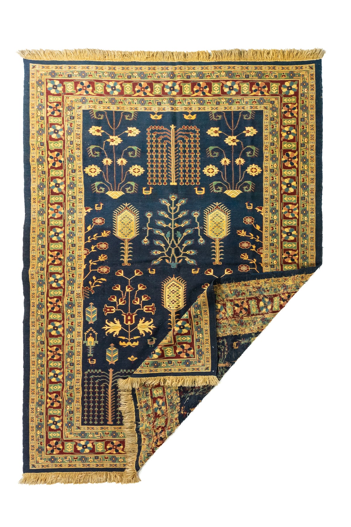 Alfombra oriental azul con una esquina doblada que muestra el reverso del tejido y los flecos laterales
