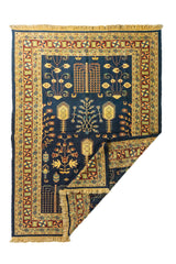 Alfombra oriental azul con una esquina doblada que muestra el reverso del tejido y los flecos laterales