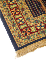 Detalle de esquina de alfombra azul con guarda floral multicolor y flecos en tono beige