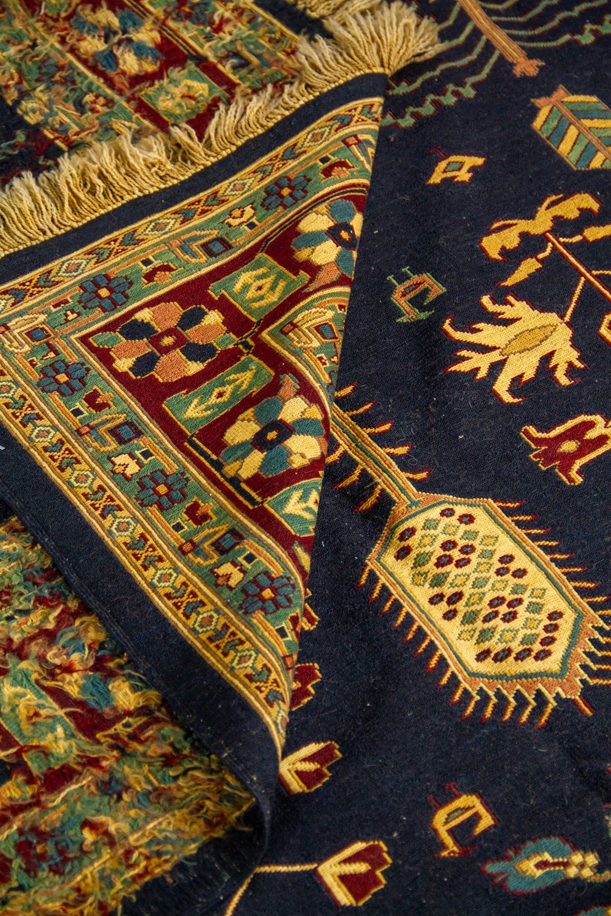 Detalle de alfombra doblada que muestra la textura del tejido, el reverso y los motivos florales tradicionales