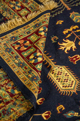 Detalle de alfombra doblada que muestra la textura del tejido, el reverso y los motivos florales tradicionales