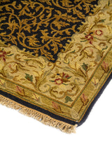 Primer plano lateral de alfombra decorativa con arabescos curvos sobre fondo oscuro y guarda clásica de inspiración floral