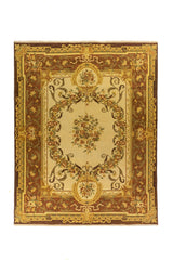 Alfombra clásica en tonos beige, marrón y dorado con composición floral central y amplia guarda ornamental