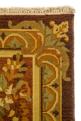 Detalle de borde superior de alfombra clásica con marco geométrico y floral en tonos marrón, beige y dorado
