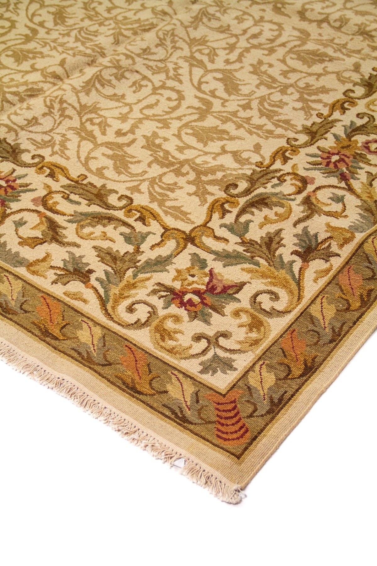 Detalle de esquina de alfombra beige con finos motivos vegetales, flores pequeñas y guarda en tonos verde y rojo