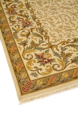 Primer plano lateral de alfombra tradicional con arabescos florales suaves y borde decorativo en tono verde suave