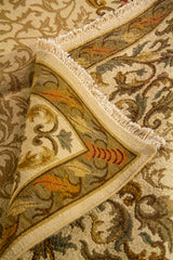 Detalle de alfombra doblada que muestra la textura del tejido, el grosor y los acabados del borde floral decorativo