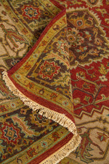 Detalle de alfombra doblada que muestra la textura del tejido, el borde decorativo y parte del medallón central