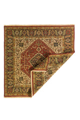 Alfombra oriental cuadrada con una esquina doblada, mostrando el reverso del tejido y su diseño geométrico tradicional en tonos cálidos.