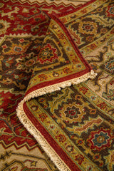 Alfombra oriental doblada mostrando la textura del tejido, el reverso y el diseño del borde ornamental con flecos.
