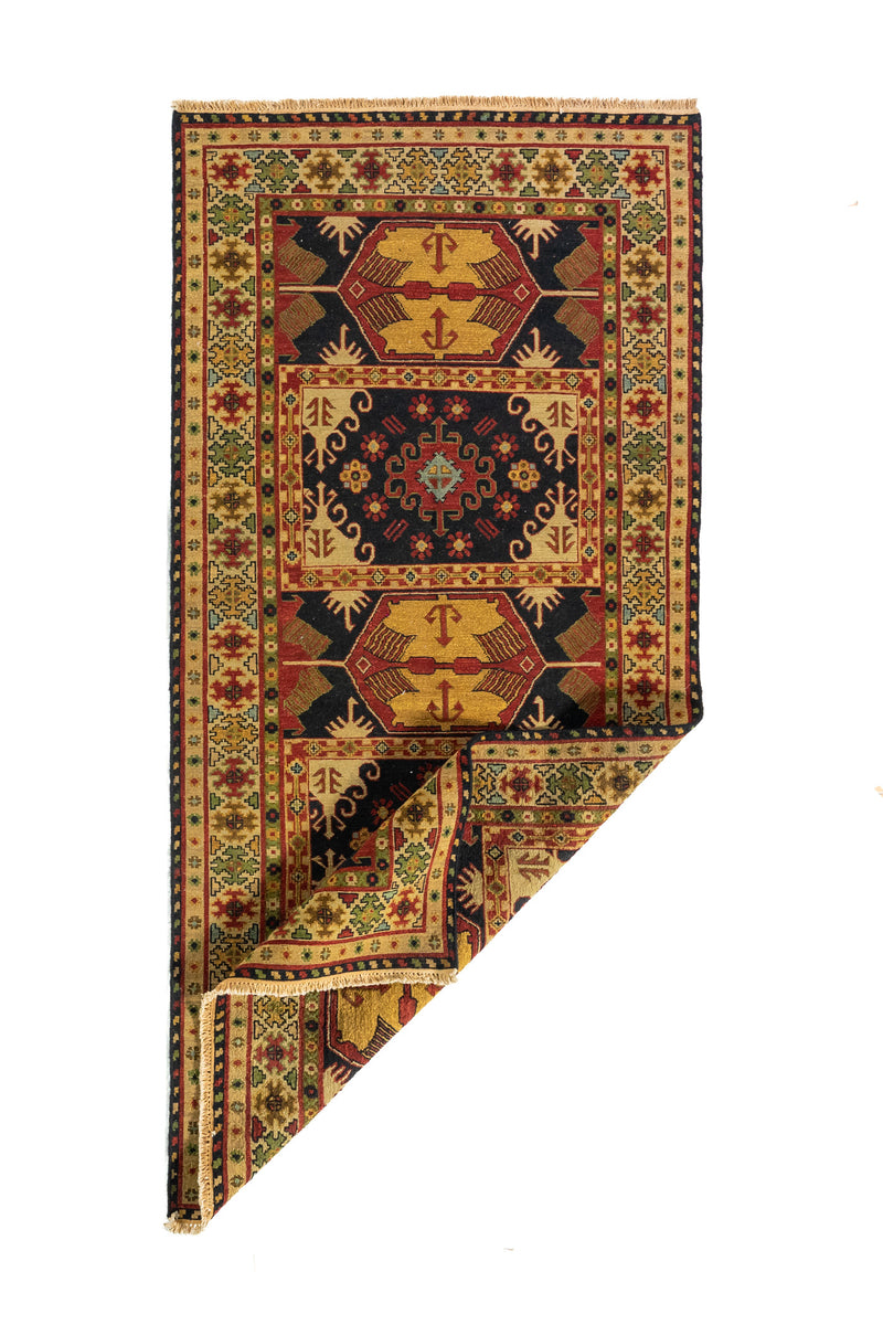 Alfombra geométrica con una esquina doblada que deja ver su reverso y su estructura textil artesanal.