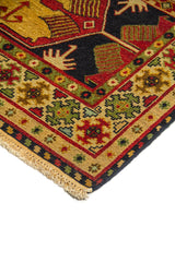Detalle de esquina de alfombra con borde geométrico en beige, rojo y verde, y diseño central en tonos azul oscuro y dorado.
