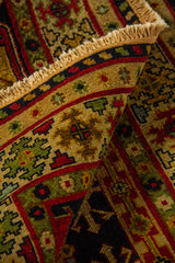 Detalle de alfombra doblada mostrando la textura del tejido, el reverso de la pieza y los flecos en tonos beige.