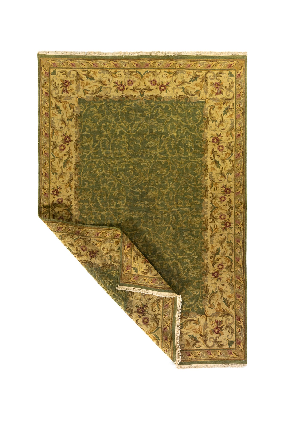 Alfombra tradicional verde oscuro y beige con una esquina doblada que muestra el reverso del tejido y su acabado artesanal