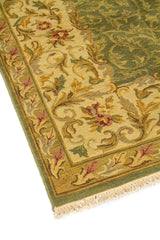 Detalle lateral de alfombra tradicional con arabescos florales, marco beige ornamentado y fondo verde de aspecto elegante