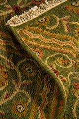 Alfombra doblada mostrando textura, grosor y reverso del tejido, con diseño repetitivo de rombos y adornos ornamentales.