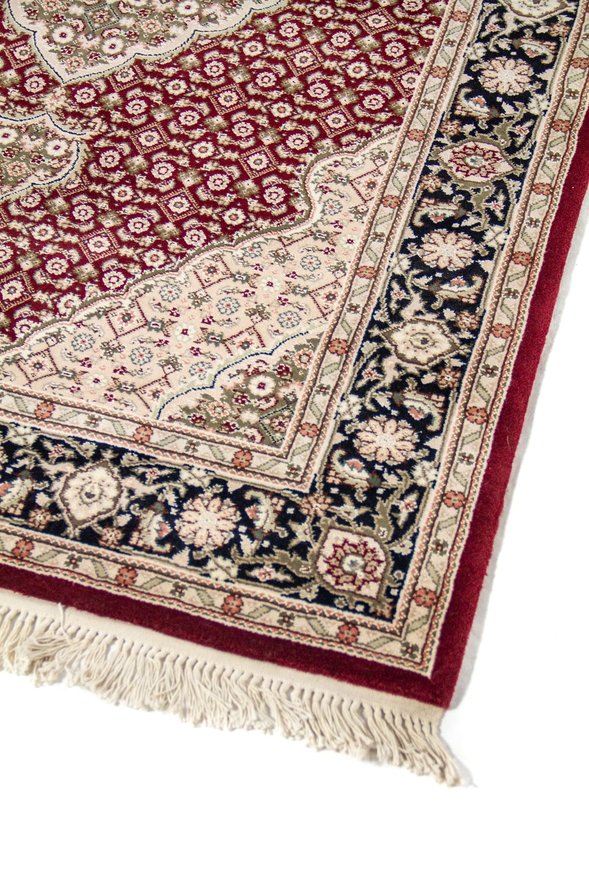 Acercamiento de alfombra clásica con patrón repetitivo en fondo rojo oscuro, borde floral oscuro y detalles ornamentales en blanco suave y tonos suaves.