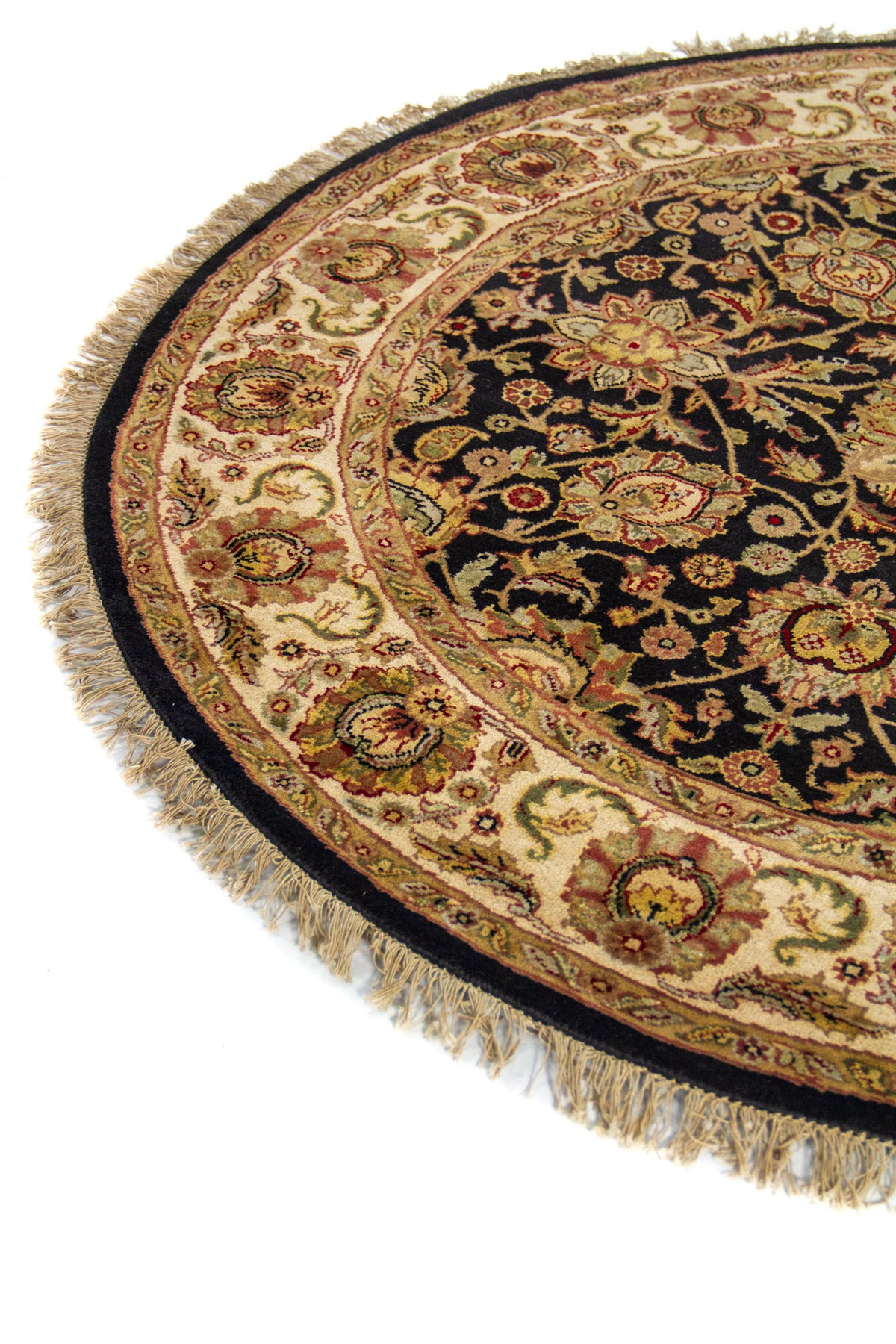 Primer plano de alfombra circular clásica con borde floral en tonos beige y dorado sobre fondo oscuro.