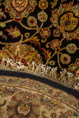 Detalle del reverso y flecos de alfombra redonda con diseño floral tradicional y acabado artesanal.