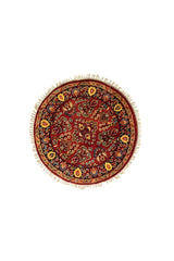 Alfombra redonda de estilo oriental en tonos rojo, azul oscuro y beige con motivos florales y flecos decorativos.