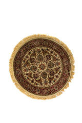 Alfombra redonda de estilo oriental en tonos beige, rojo y verde oliva con diseño floral clásico y flecos decorativos.