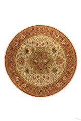 Alfombra redonda oriental en tonos beige, rojo y dorado con medallón central y motivos florales geométricos.