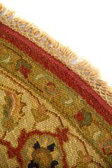 Primer plano del borde de alfombra redonda con flecos decorativos y patrones florales en tonos cálidos.